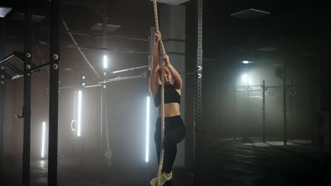 sporty-exercise-for-endurance-and-power-woman-is-climbing-rope-in-fitness-hall